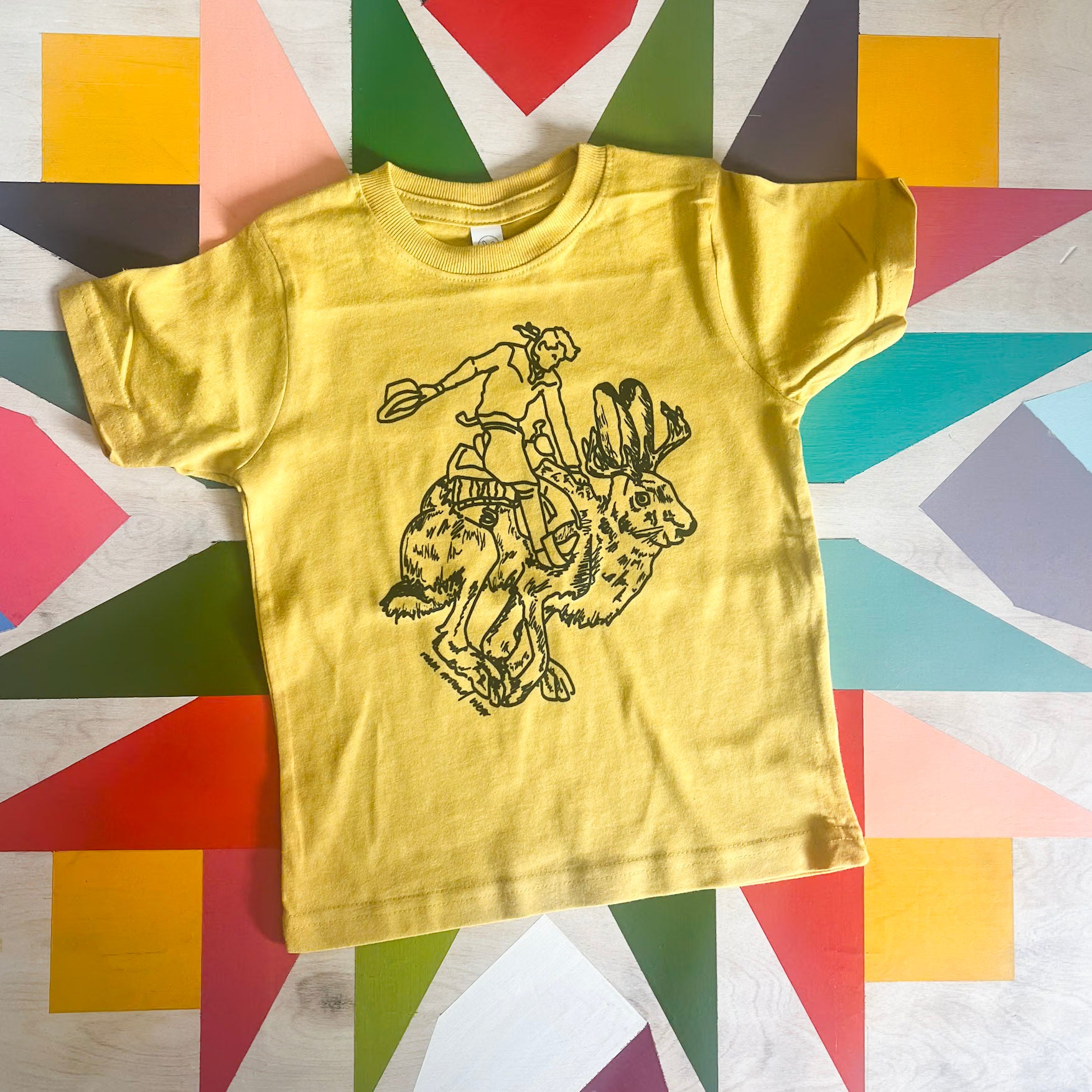 Black Jackalope and Rider toddler mustard tee. Roam Around Wear is a Wyoming t-shirt company based out of Gillette, Wyoming. Artisan Designed.