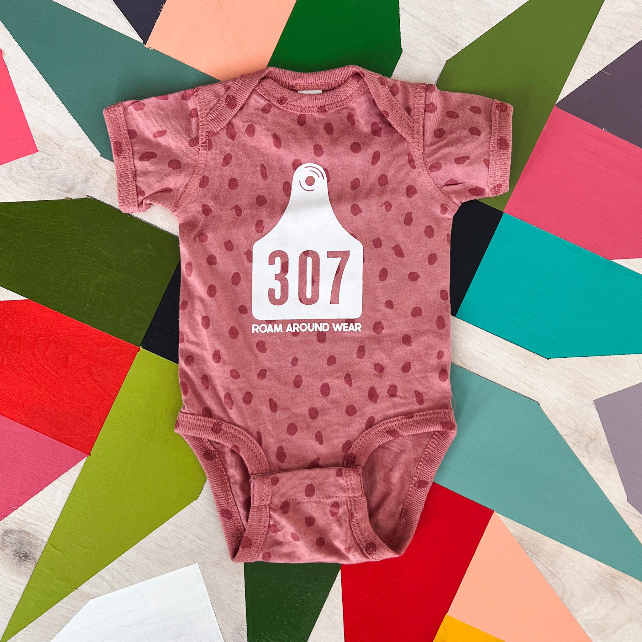 Pink Infant 307 Onesie. Wyoming Cow Tag Baby Shirt. Roam Around Wear is a Wyoming t-shirt company based out of Gillette, Wyoming