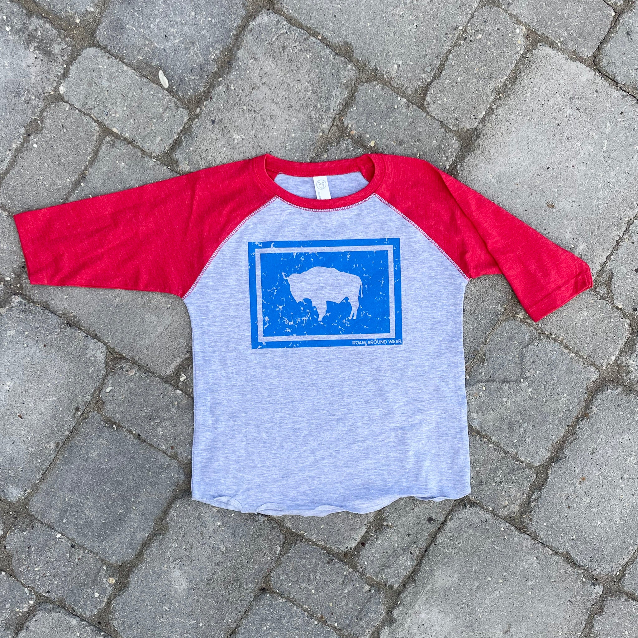 Wyoming flag toddler red, gray, blue tee. Roam Around Wear is a women owned Wyoming T-Shirt company based out of Gillette, Wyoming.